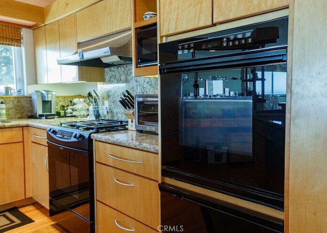 kitchen with black appliances, light stone countertops, backsplash, and light hardwood / wood-style flooring