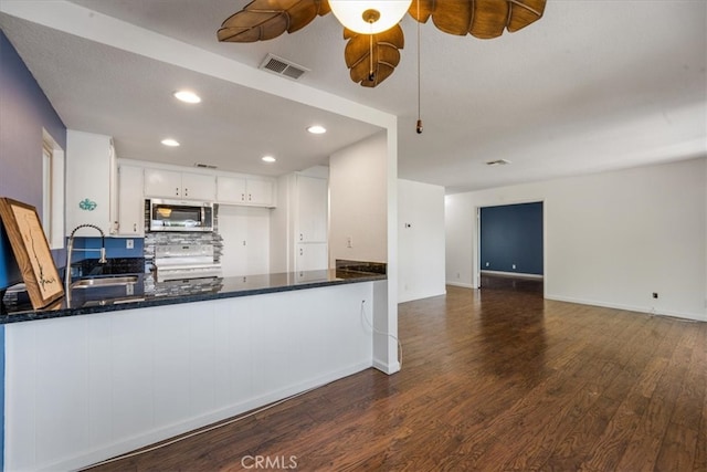 kitchen featuring white cabinets, stove, sink, kitchen peninsula, and dark hardwood / wood-style flooring