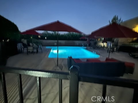 pool at dusk featuring a patio area