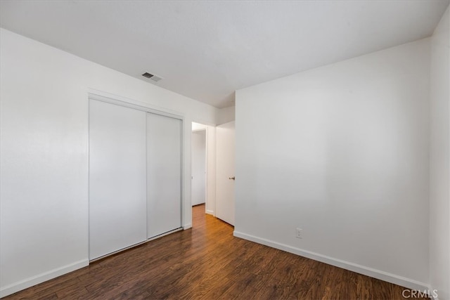 unfurnished bedroom featuring dark hardwood / wood-style floors and a closet