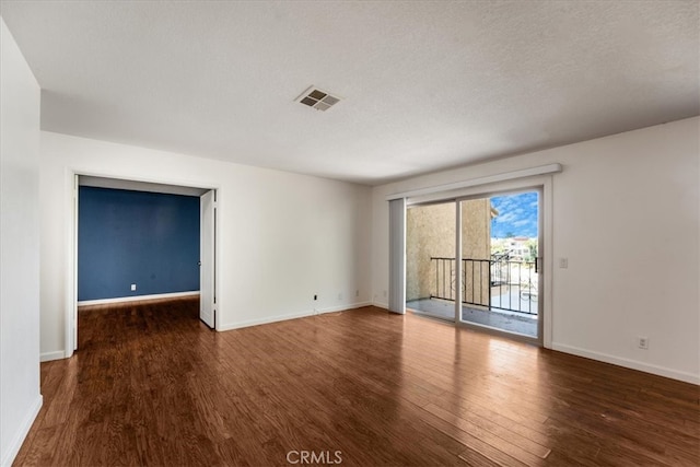 empty room with a textured ceiling and dark hardwood / wood-style flooring