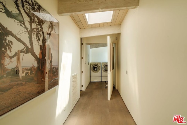 hall featuring hardwood / wood-style flooring, beam ceiling, independent washer and dryer, and a skylight