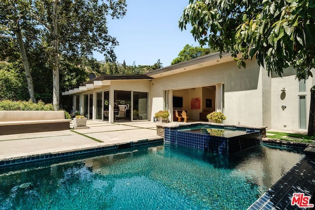 back of property featuring a patio area and a pool with hot tub