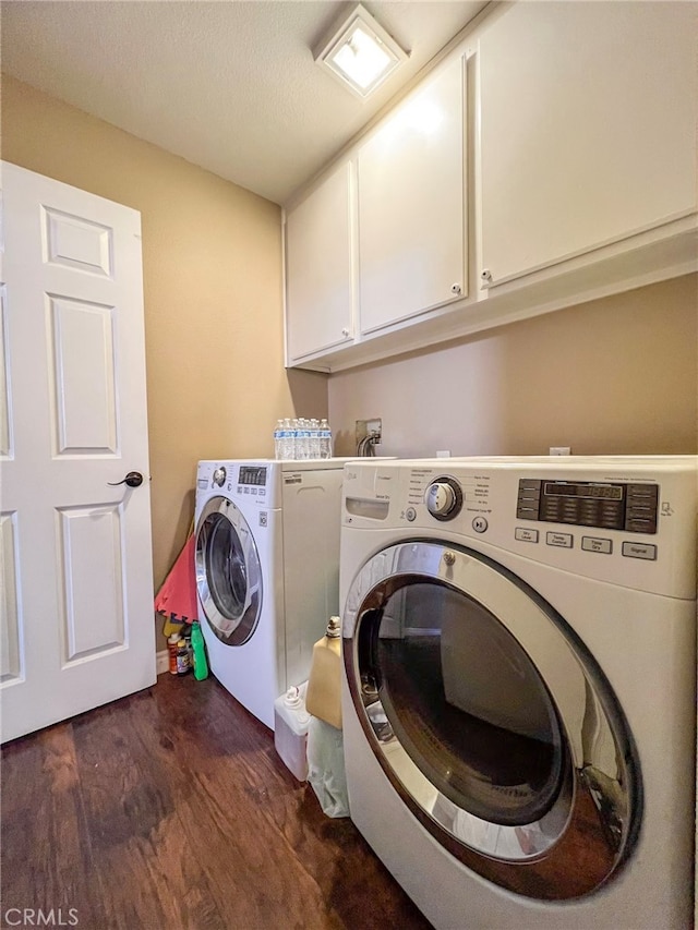 laundry area with cabinets, a textured ceiling, washing machine and dryer, and dark hardwood / wood-style flooring