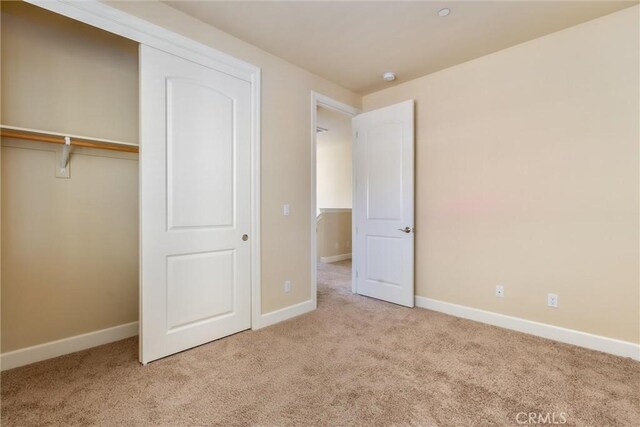 unfurnished bedroom featuring carpet flooring, baseboards, and a closet