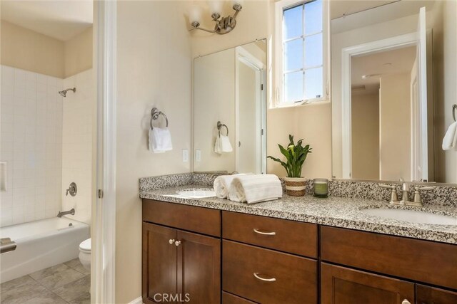 full bathroom featuring tiled shower / bath, vanity, and toilet