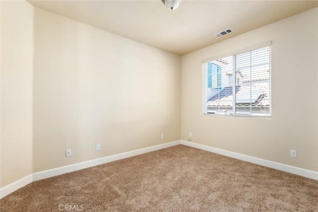 empty room with visible vents, carpet floors, and baseboards