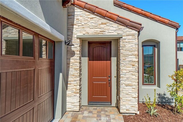 property entrance featuring stone siding and stucco siding