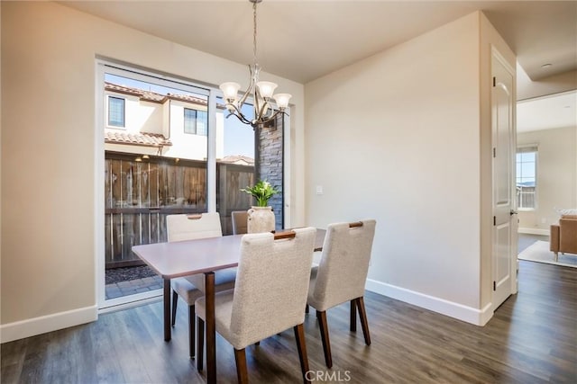 dining space with dark wood finished floors, a notable chandelier, and baseboards