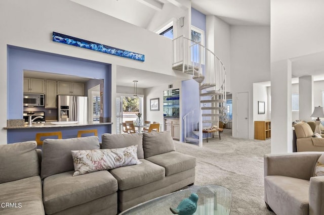 carpeted living room with beam ceiling and high vaulted ceiling