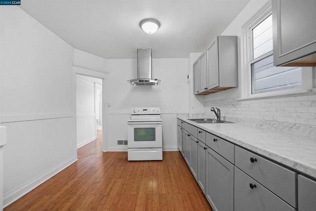 kitchen with sink, wall chimney range hood, white electric range, gray cabinets, and light hardwood / wood-style floors