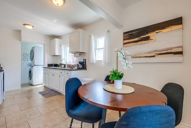 dining space featuring light tile patterned floors, stacked washer and clothes dryer, and sink