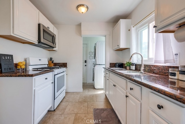 kitchen featuring dark stone counters, white appliances, and white cabinets