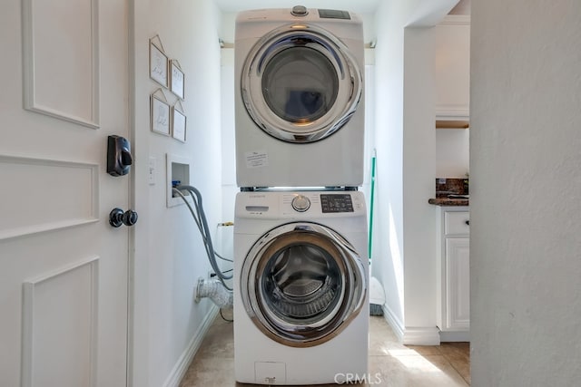 laundry area featuring light tile patterned floors and stacked washer / drying machine