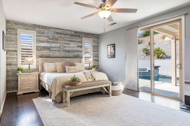 bedroom featuring ceiling fan, dark hardwood / wood-style floors, wood walls, and access to outside