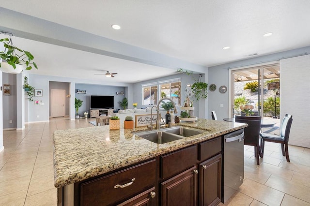 kitchen featuring dishwasher, an island with sink, sink, light stone counters, and ceiling fan