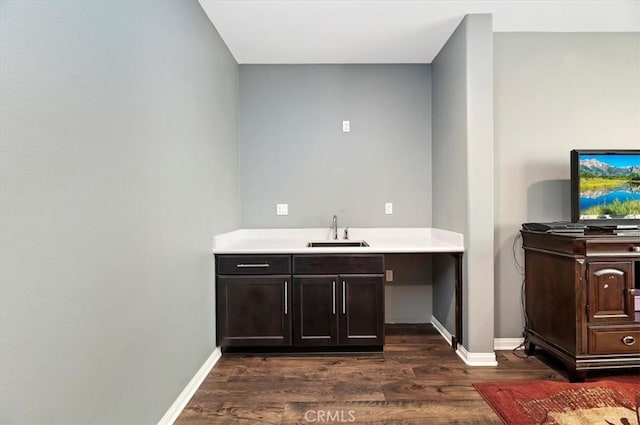 bar featuring dark wood-type flooring, sink, and dark brown cabinetry