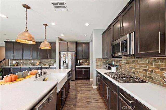 kitchen featuring dark brown cabinetry, appliances with stainless steel finishes, decorative light fixtures, decorative backsplash, and sink