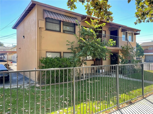 view of front of house featuring a balcony and a front yard