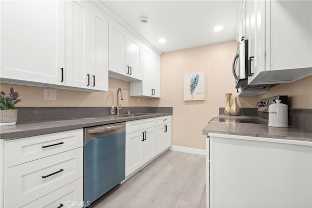 kitchen with light hardwood / wood-style floors, appliances with stainless steel finishes, sink, and white cabinetry