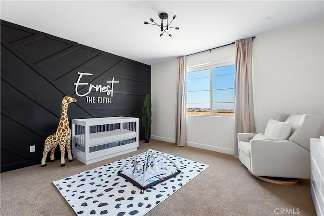 carpeted bedroom with a nursery area and a notable chandelier