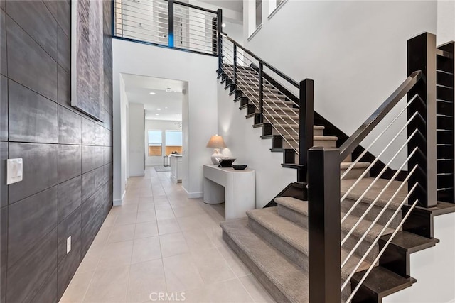 stairs featuring tile patterned flooring, tile walls, and a high ceiling