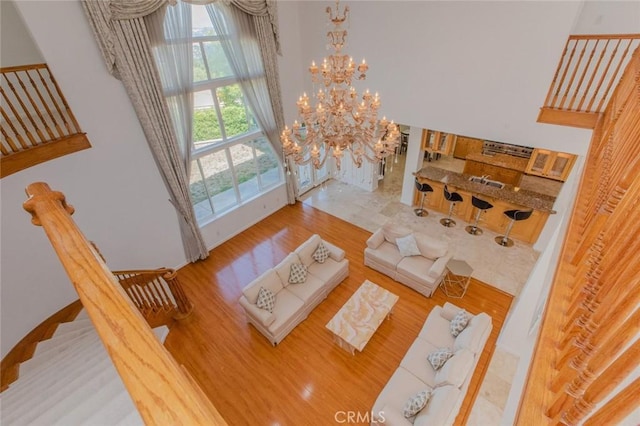 living room featuring hardwood / wood-style floors, a towering ceiling, and an inviting chandelier