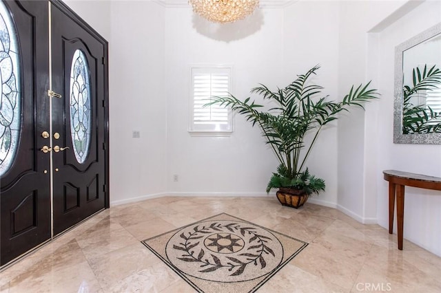 foyer entrance with a chandelier and ornamental molding