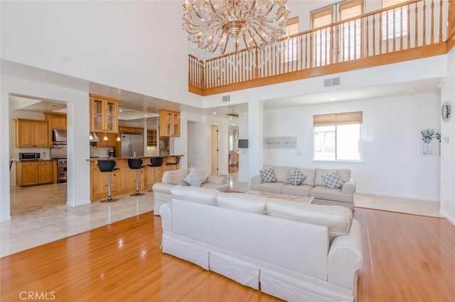 living room with a high ceiling, light hardwood / wood-style flooring, and a notable chandelier