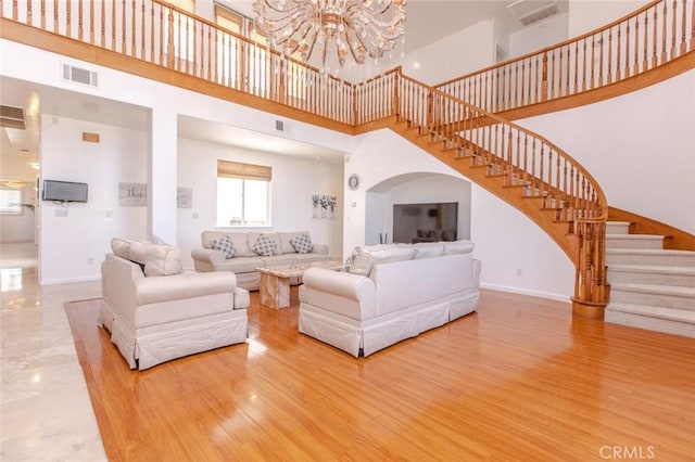 living room featuring hardwood / wood-style flooring, a notable chandelier, and a towering ceiling