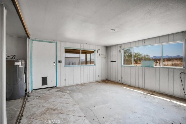 unfurnished room with a mountain view, wooden walls, and water heater