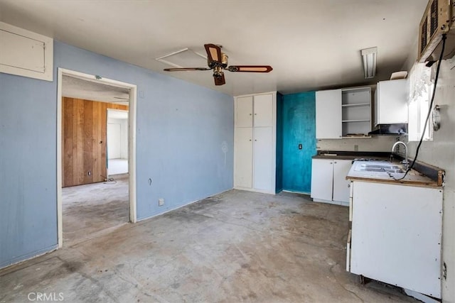 kitchen featuring ceiling fan, white cabinetry, sink, and wall chimney range hood