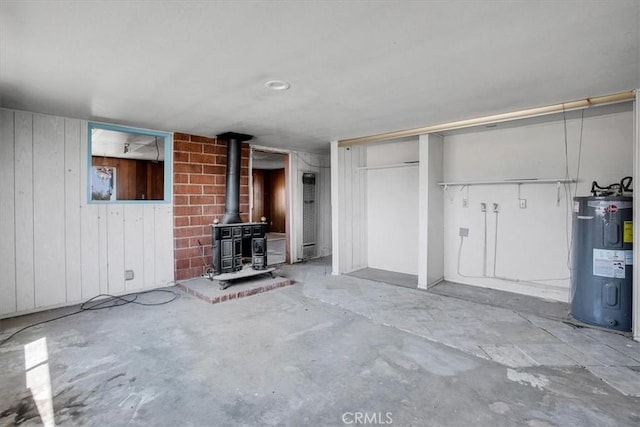 unfurnished living room with a wood stove, electric water heater, and wood walls