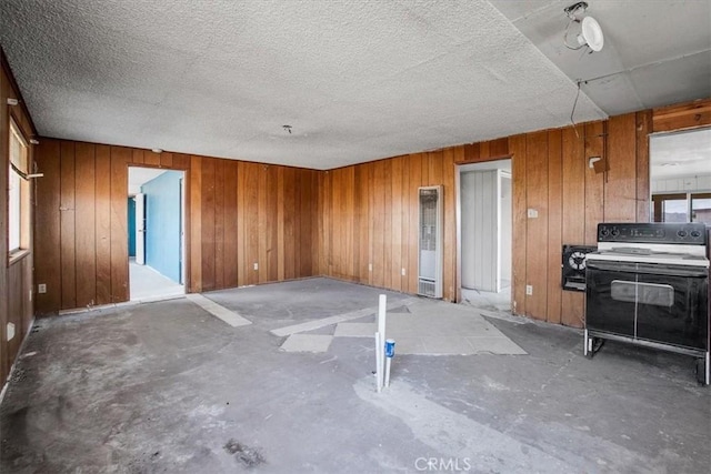 interior space featuring concrete flooring, a textured ceiling, and wooden walls