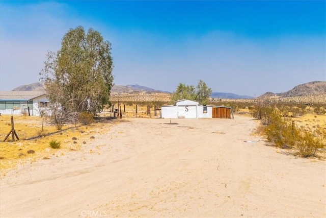 view of yard with a mountain view, a rural view, and an outbuilding