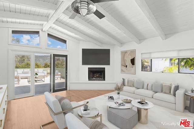 living room featuring ceiling fan, light wood-type flooring, lofted ceiling with beams, and a wealth of natural light