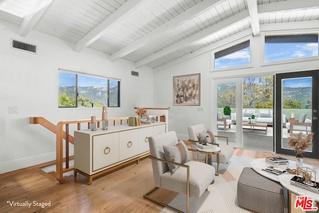 living area featuring beamed ceiling, plenty of natural light, and light hardwood / wood-style floors