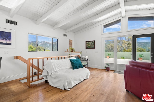 bedroom with multiple windows, light hardwood / wood-style floors, beam ceiling, and access to exterior