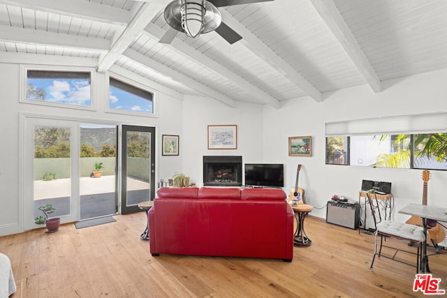 living room with ceiling fan, light hardwood / wood-style flooring, lofted ceiling with beams, and a wealth of natural light