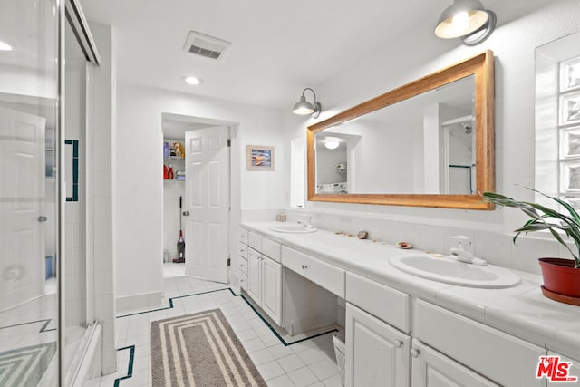 bathroom featuring tile patterned floors, a shower with door, and vanity