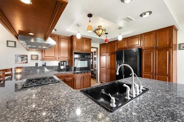 kitchen with sink, ventilation hood, hanging light fixtures, a tray ceiling, and black appliances