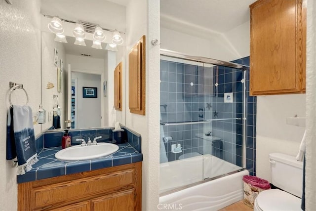 full bathroom with vanity, enclosed tub / shower combo, and toilet