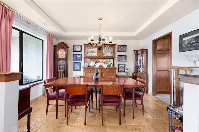 dining area with a notable chandelier and a raised ceiling