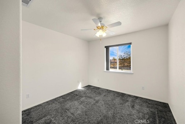 spare room featuring dark colored carpet, a textured ceiling, and ceiling fan