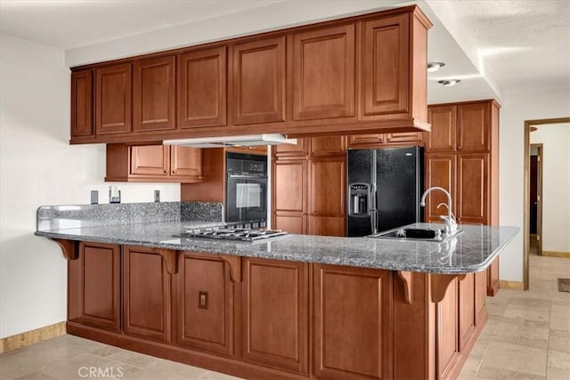 kitchen with kitchen peninsula, sink, a kitchen bar, dark stone counters, and black appliances