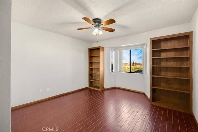 unfurnished room with ceiling fan, dark wood-type flooring, and a textured ceiling