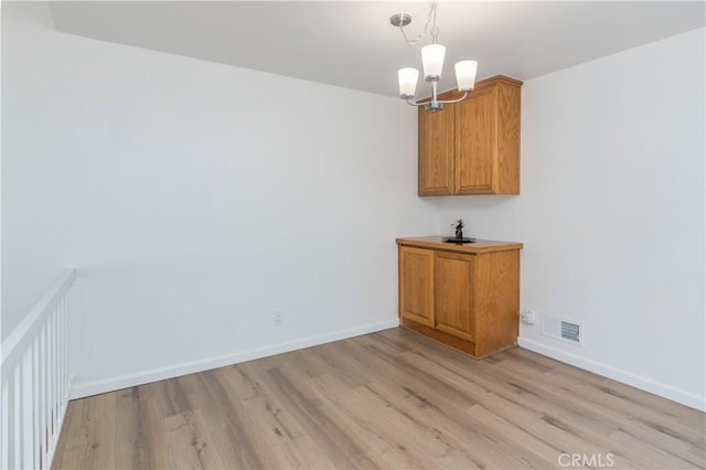 unfurnished dining area with light wood-type flooring and a notable chandelier