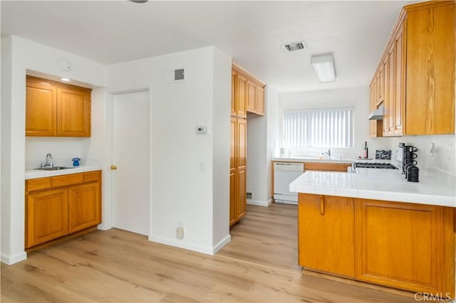 kitchen with dishwasher, tile countertops, kitchen peninsula, sink, and light wood-type flooring