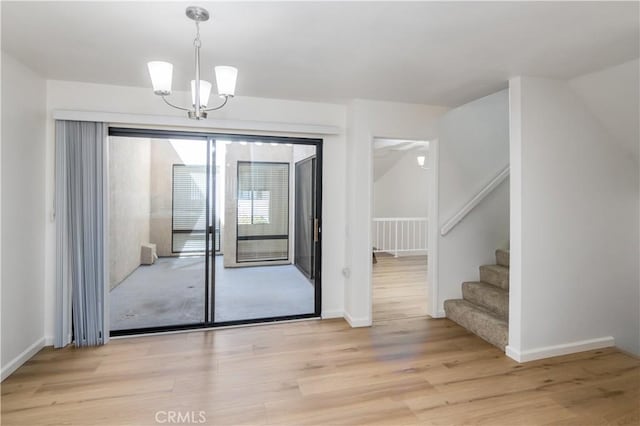 doorway to outside featuring light hardwood / wood-style floors and an inviting chandelier