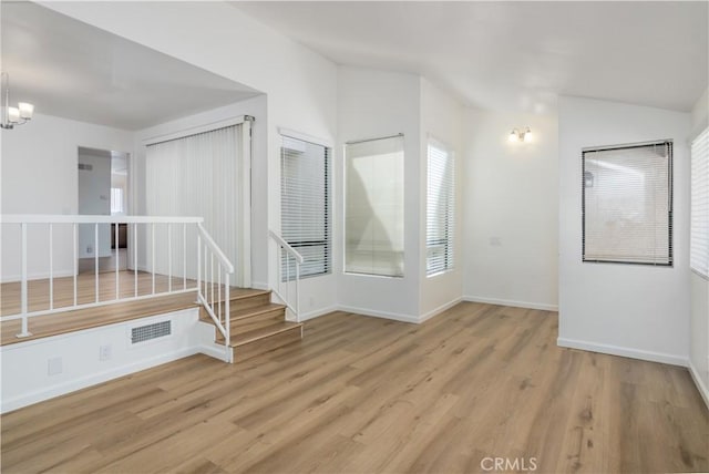 spare room with a notable chandelier and light wood-type flooring